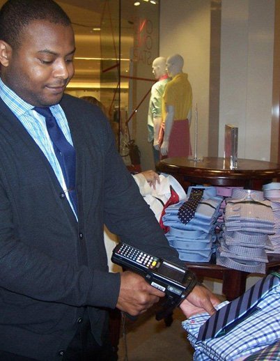MACY’S RFID:  Macy’s rolled out RFID to all of its stores. Above, a Macy’s file photo of a Macy’s clerk working with an RFID reader. Photo courtesy of Macy’s.
