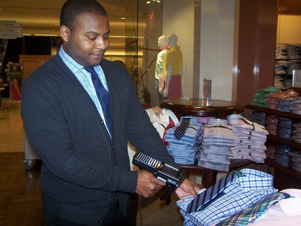 MACY’S RFID:  Macy’s rolled out RFID to all of its stores. Above, a Macy’s file photo of a Macy’s clerk working with an RFID reader. Photo courtesy of Macy’s.