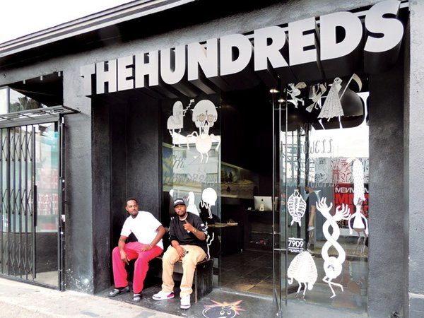 STREETWEAR HOME: The Hundreds boutique, 100 yards off of Los Angeles’ Fairfax Avenue, is part of the concentration of stores making the thoroughfare a capital of streetwear style. At right is a worker at The Hundreds who gave his name as 5ive. Also pictured is 5ive’s friend, who gave his name as Cali_Ant_Tay. Photos by Andrew Asch