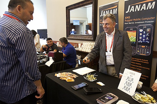 SCAN MAN: Janam showing an attendee how their scanners work and what their booth is all about.