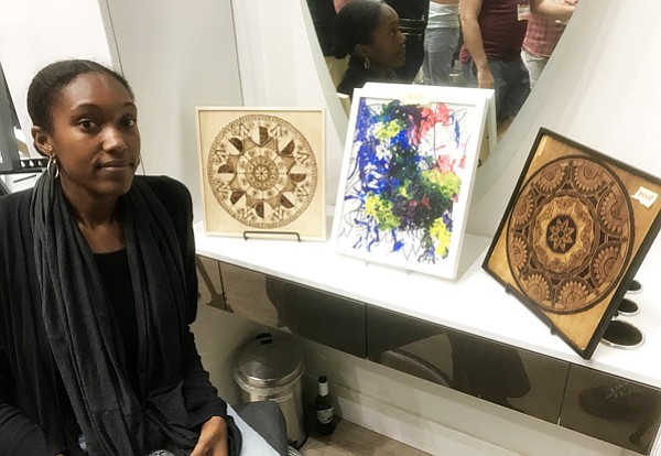 Leahcim Robinson with two of her brunt-wood pieces 