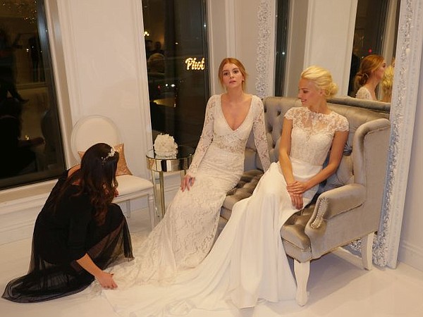 Chelsey Clayton fixes the gown of model Casey Engleson. Seated next to her is Chanel Forsstrom. They're both wearing Winnie Couture 2019 collection.