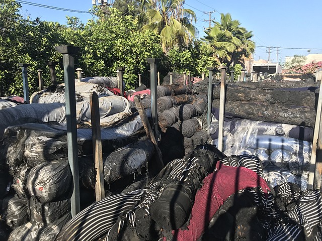 Piles of charred fabric sit outside of Lavitex following a fire at the wholesaler's building.
